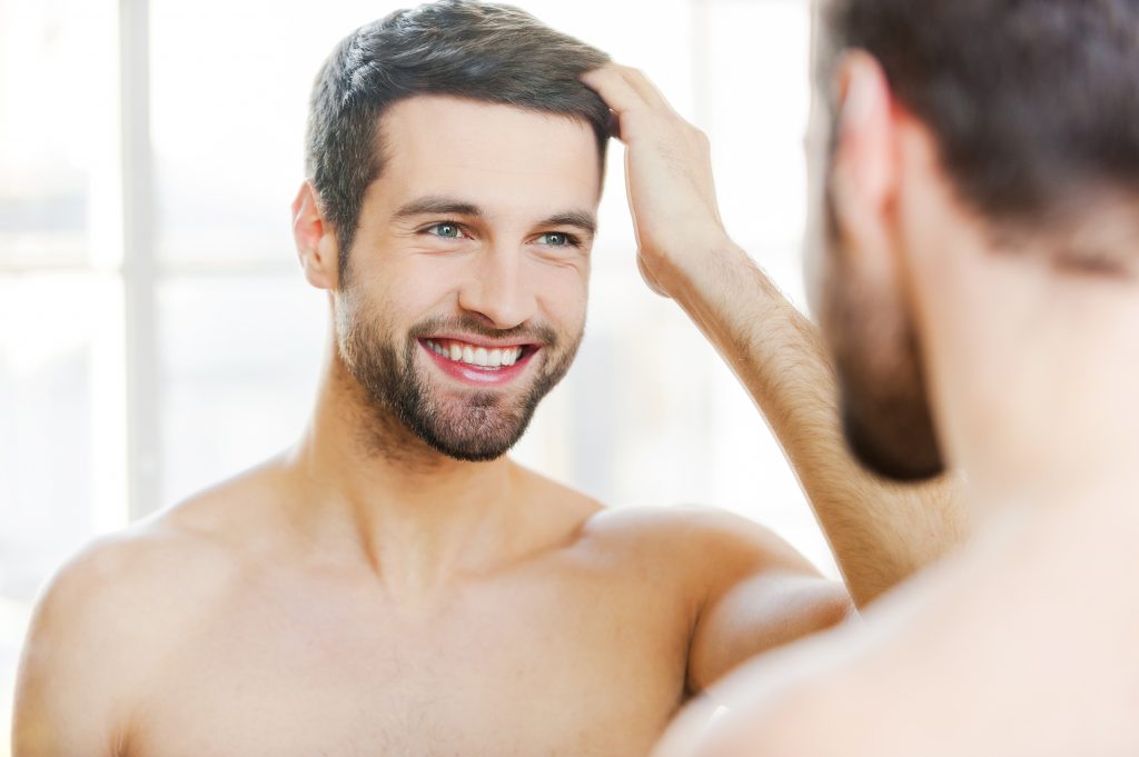 Man touching his hair while looking at the mirror