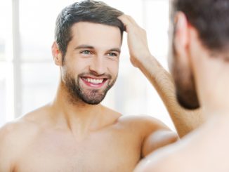 Man touching his hair while looking at the mirror