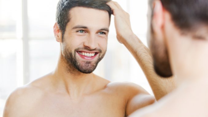 Man touching his hair while looking at the mirror