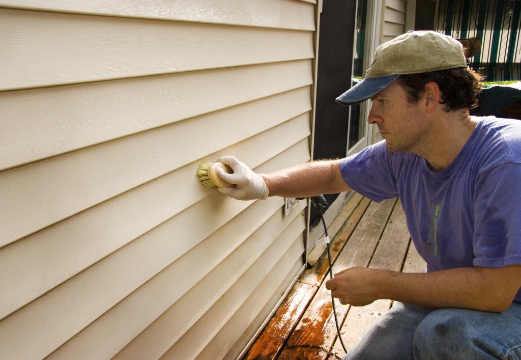 Guy washing siding with brush