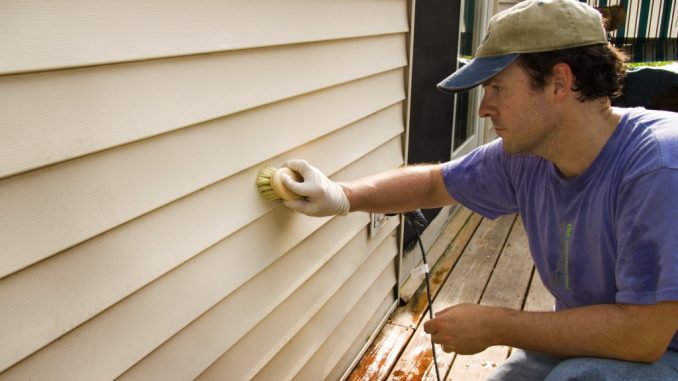 Guy washing siding with brush