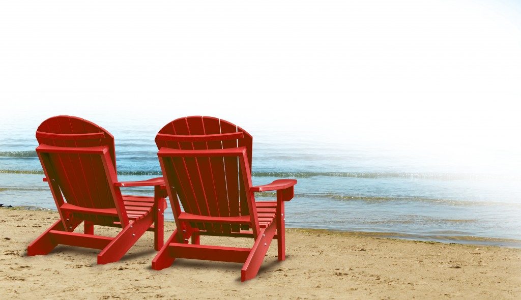 red wooden beach chairs placed by the ocean shore