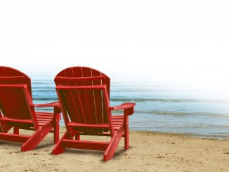 red wooden beach chairs placed by the ocean shore