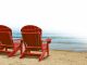 red wooden beach chairs placed by the ocean shore