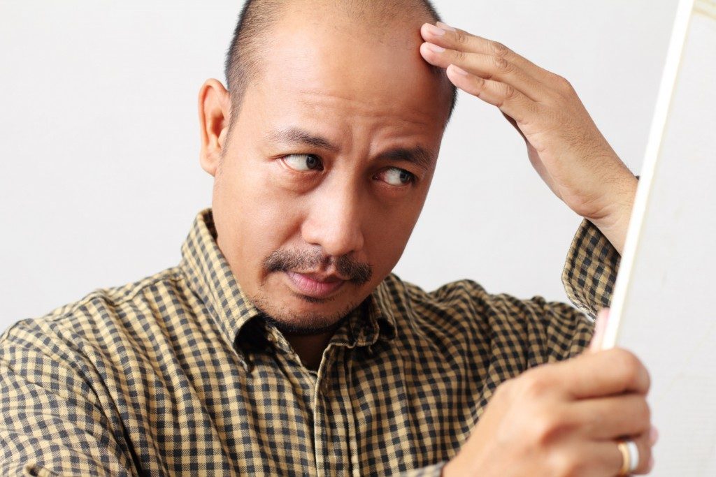 man touching his thinning hair