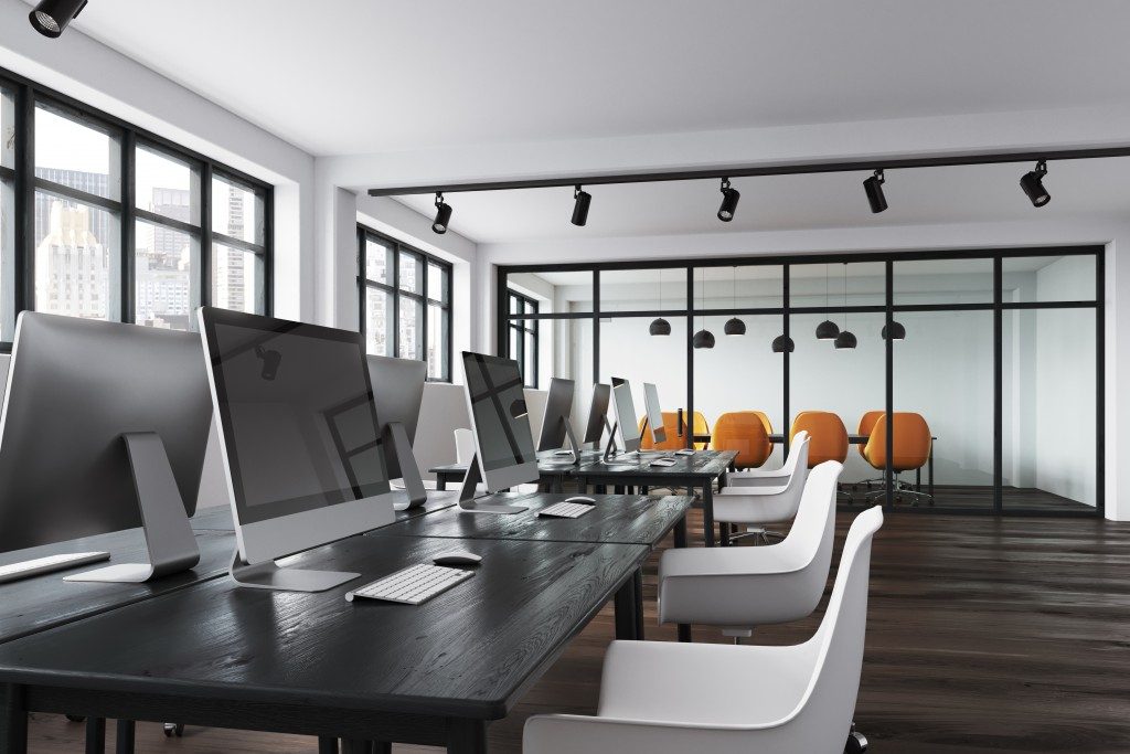 minimalist office workspace with white chairs and silver desktops