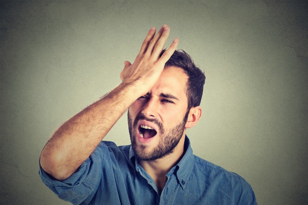 irritated man holding his forehead