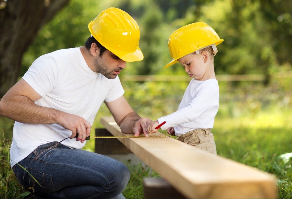 Little son helping his father with building house