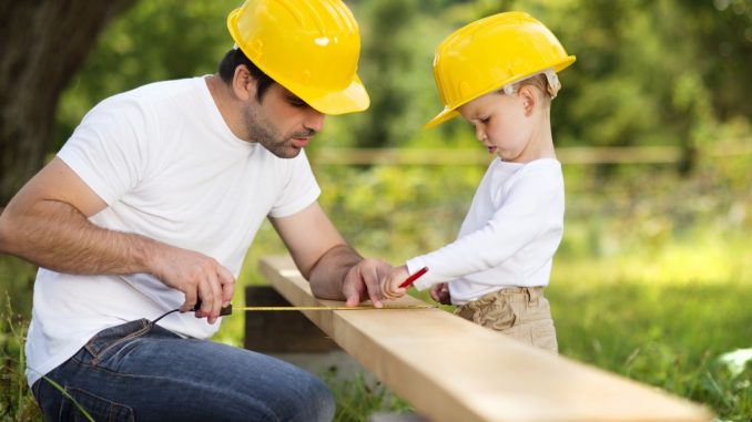 Little son helping his father with building house