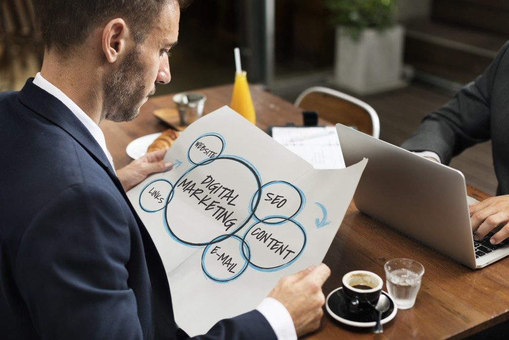 businessman holding a paper that shows different components of digital marketing