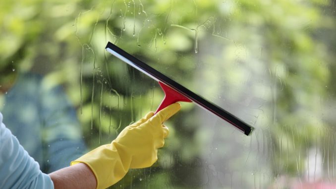 person cleaning window with squeegee