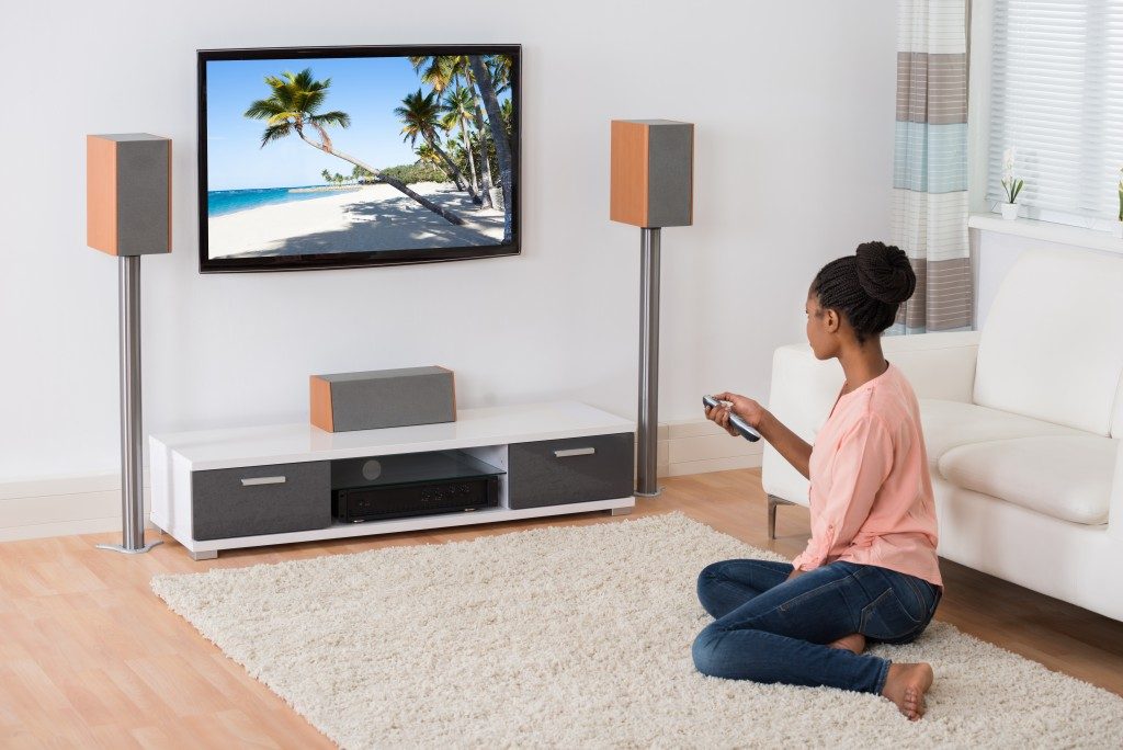 woman sitting on the carpet floor while watching tv