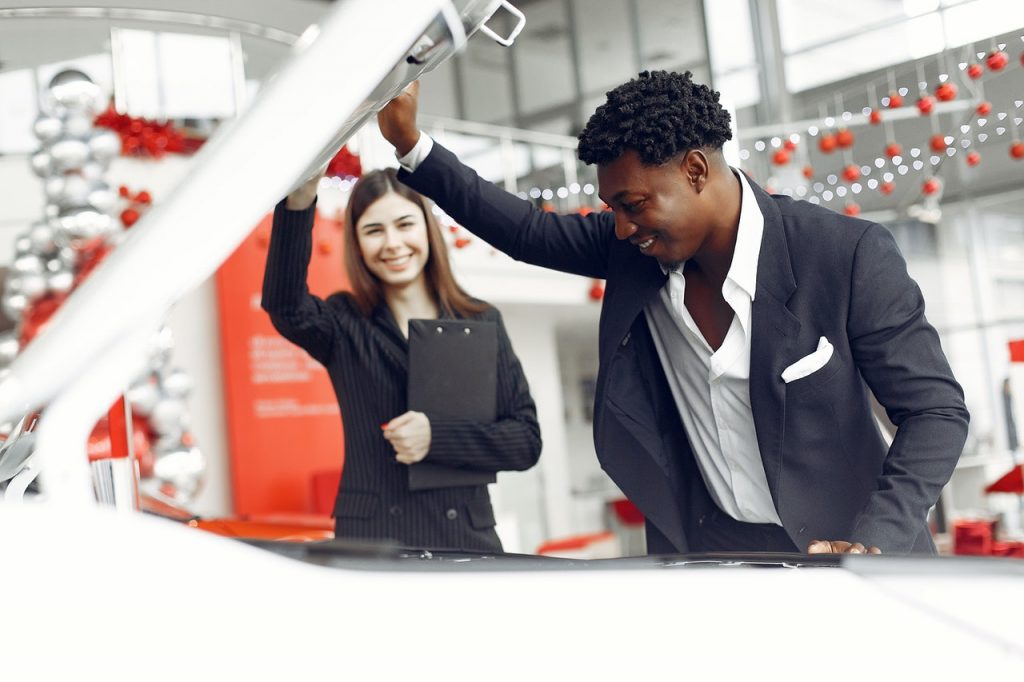man inspecting the hood of a car