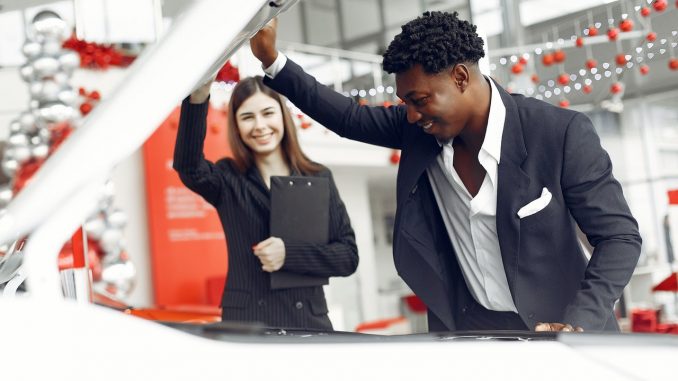 man inspecting the hood of a car