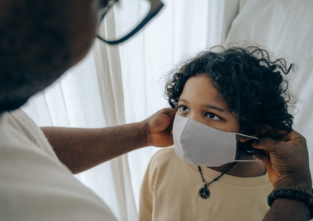 putting on face mask on little girl