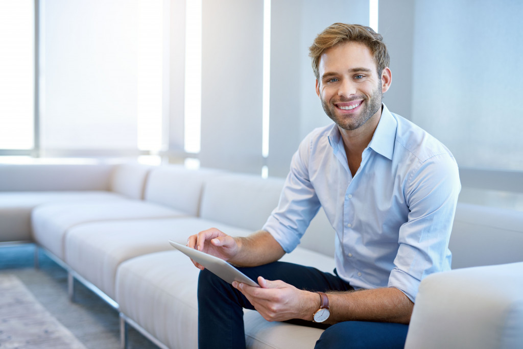man smiling while holding a tablet